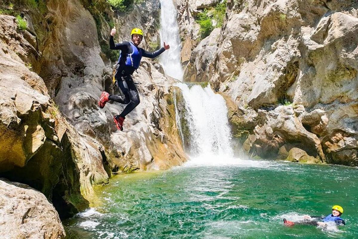dues persones saltant d'una cascada a un riu