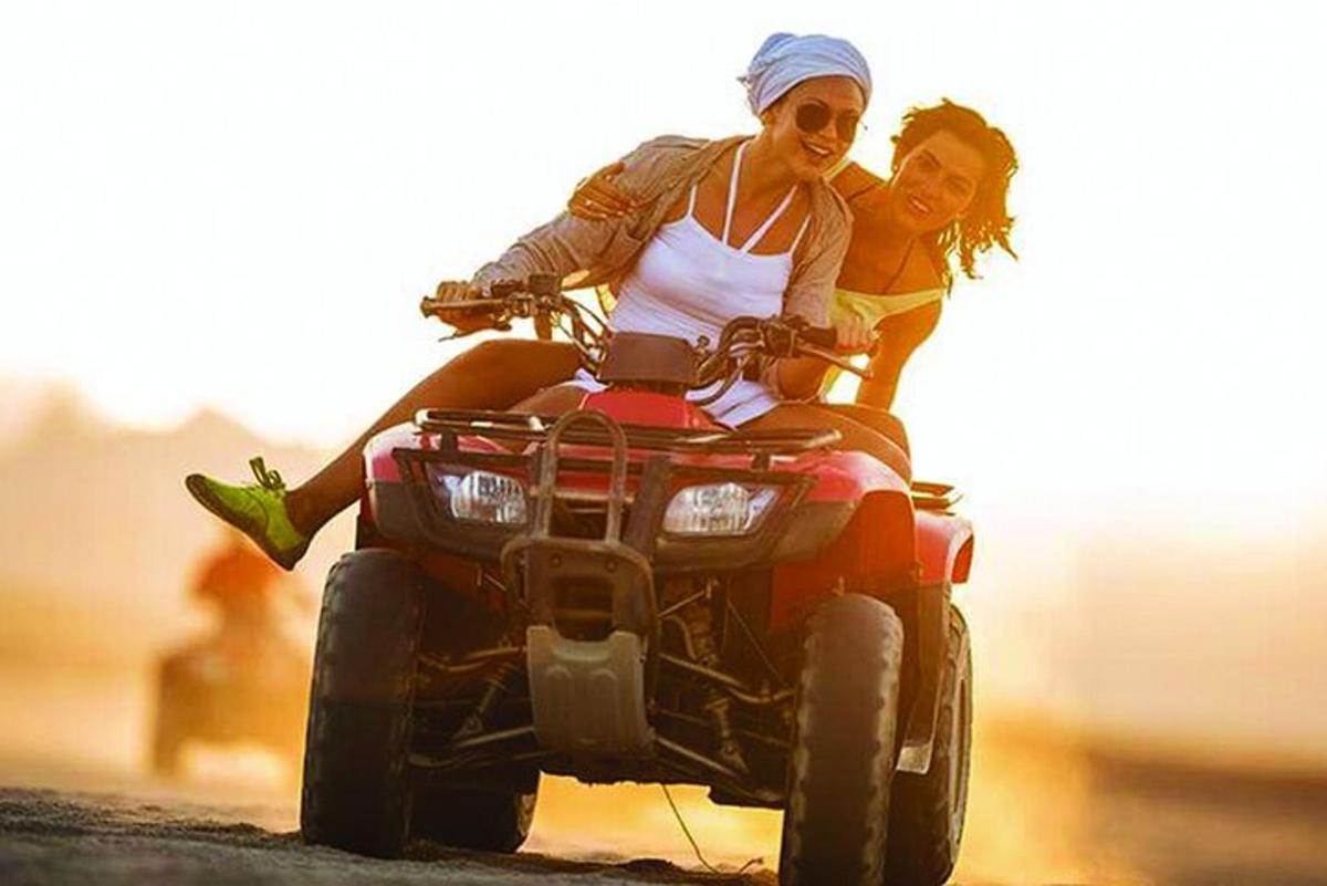 two women riding a quad bike on the road