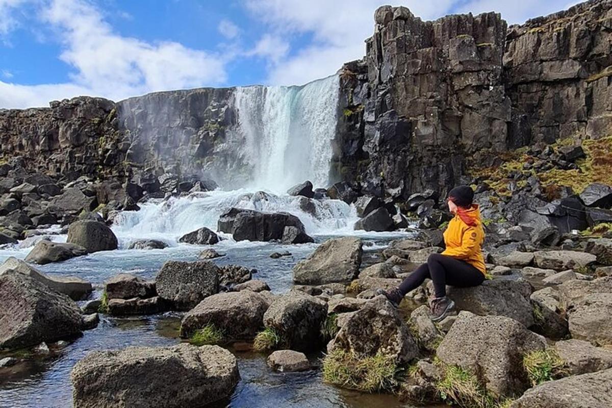 seseorang yang duduk di atas batu di hadapan air terjun