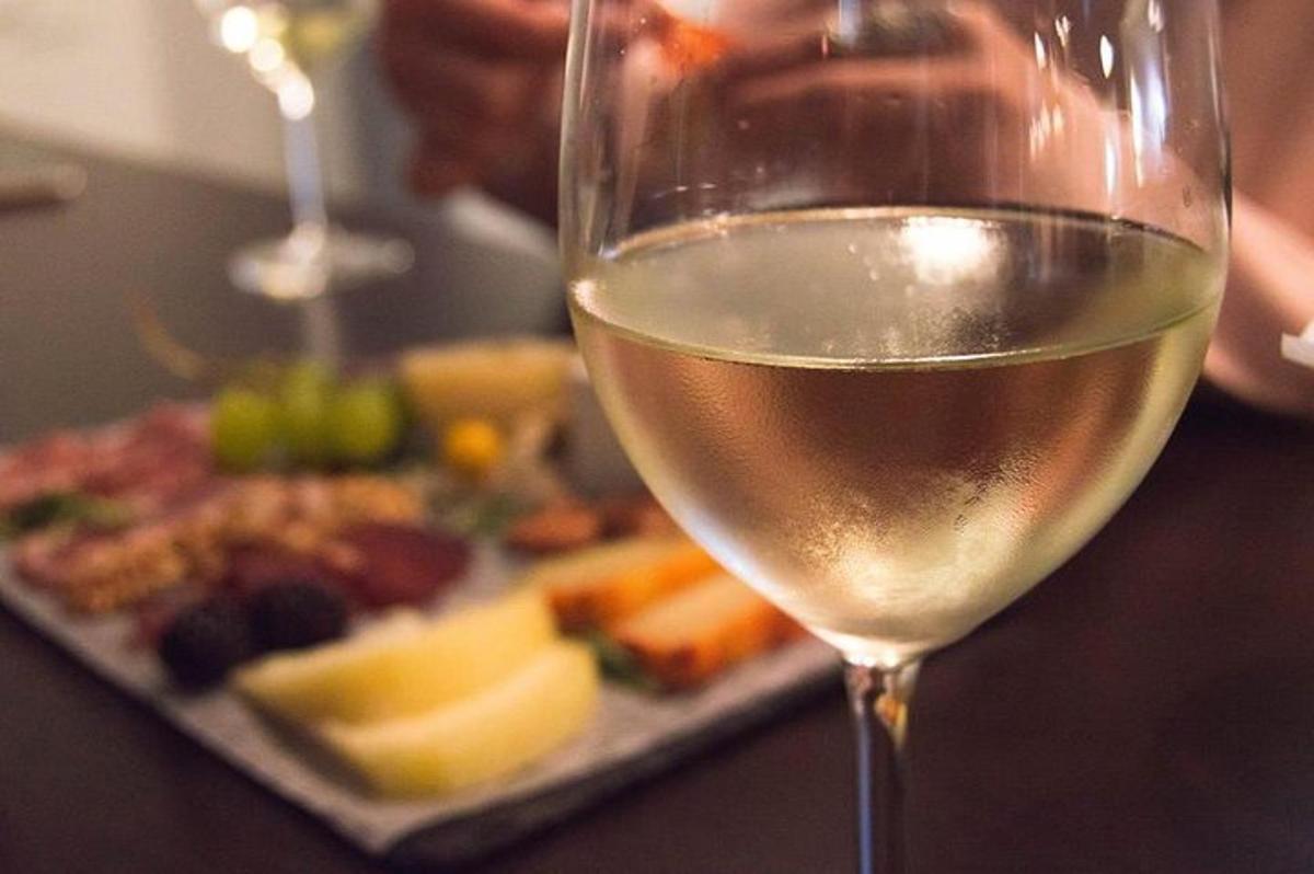 una copa de vi blanc al costat d'un plat de menjar