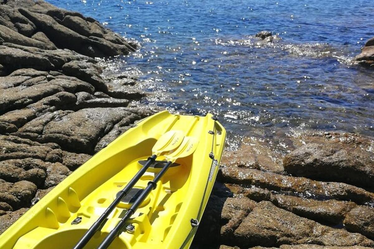 a yellow kayak sitting on the rocks next to the water