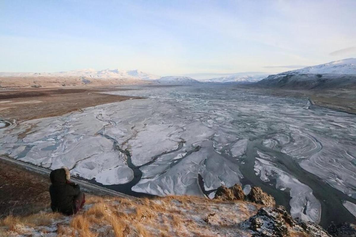 maður situr á hæð og horfir yfir frosna á