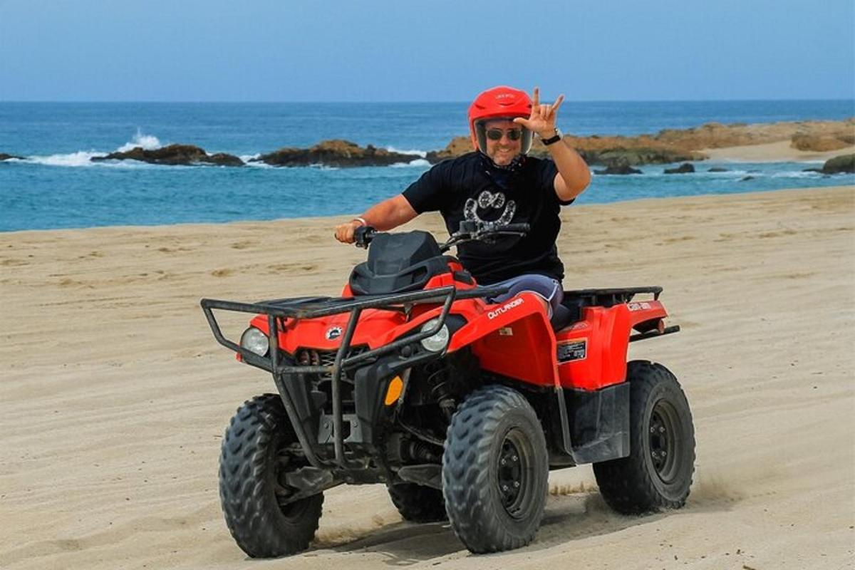 um homem andando de quadriciclo na praia