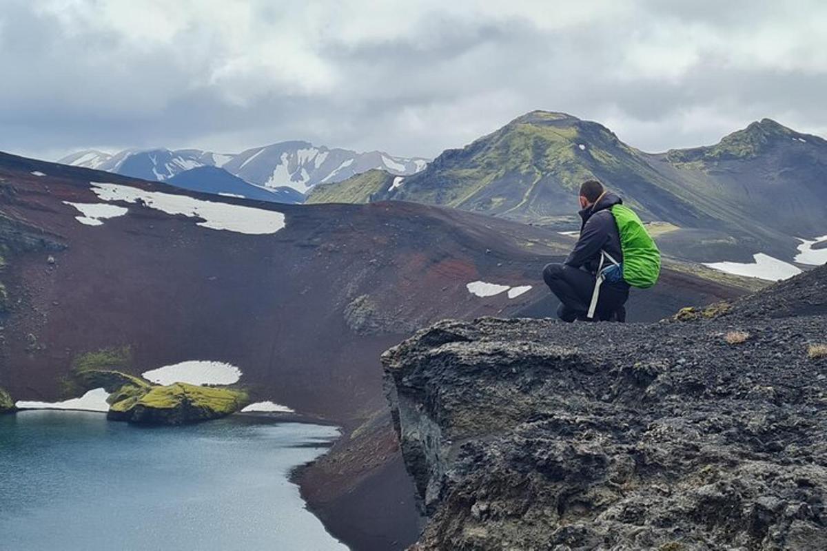 un uomo seduto su una roccia che guarda una montagna