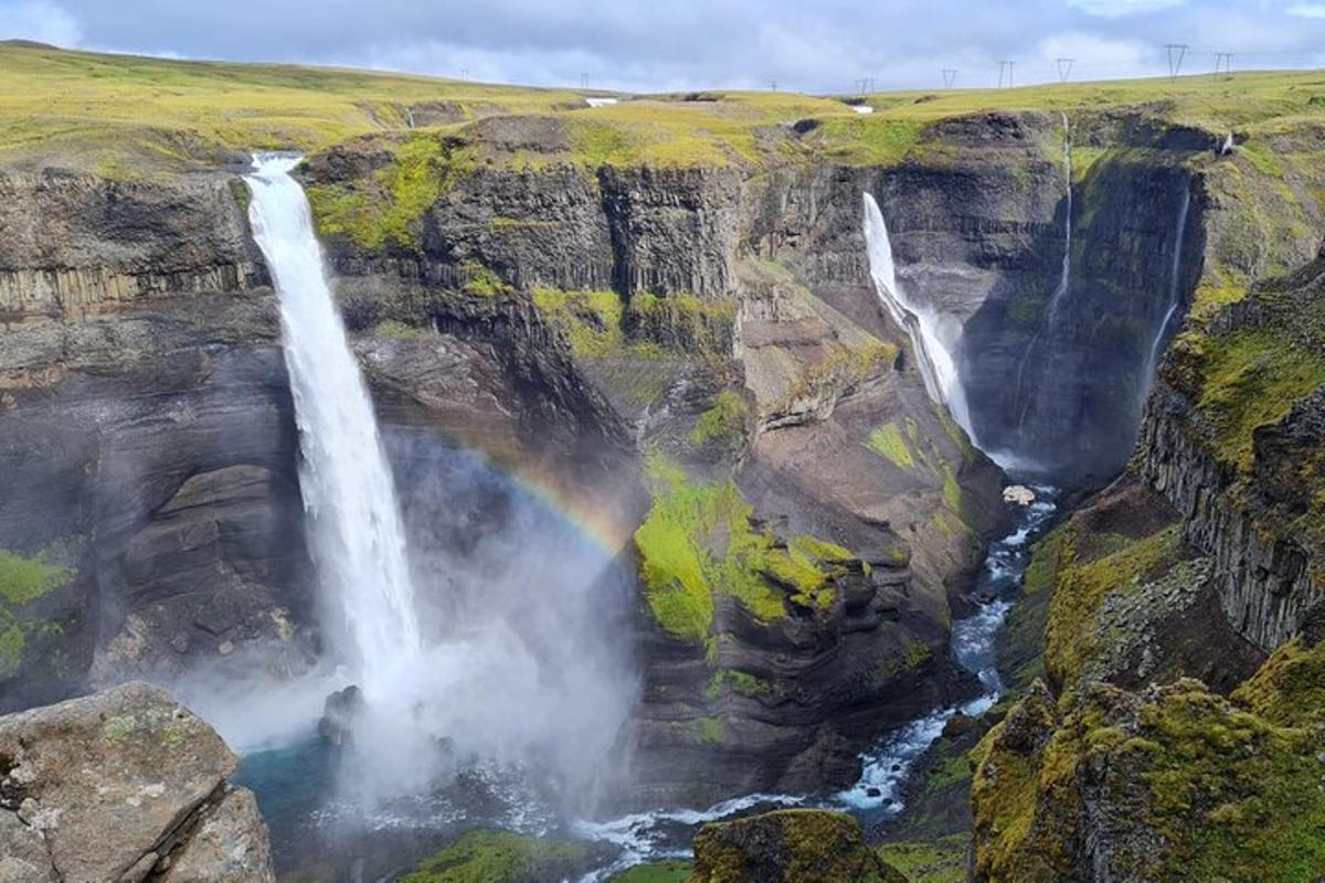 um arco-íris sobre uma cachoeira em um penhasco