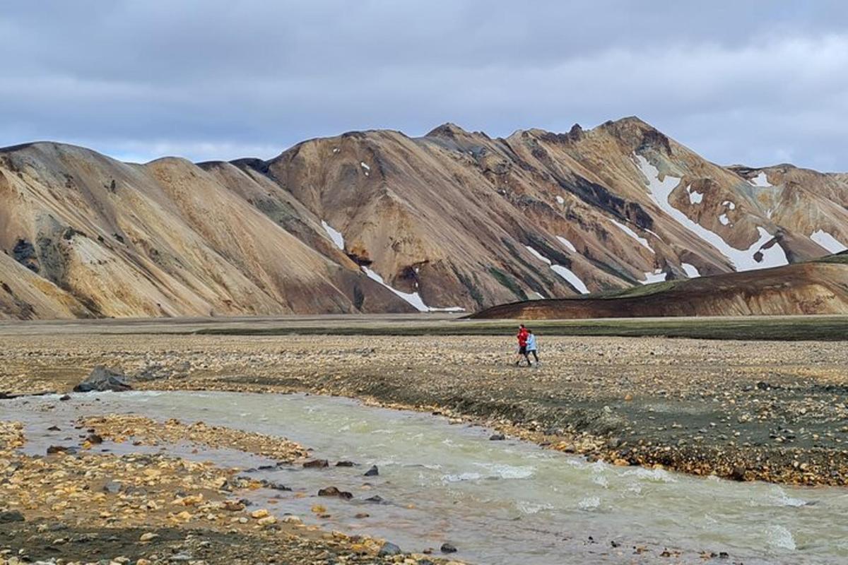 una persona in piedi su un campo roccioso con montagne sullo sfondo