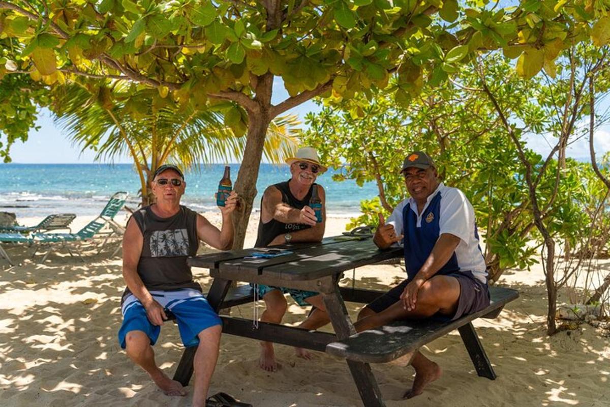 three people sitting at a picnic table on the beach