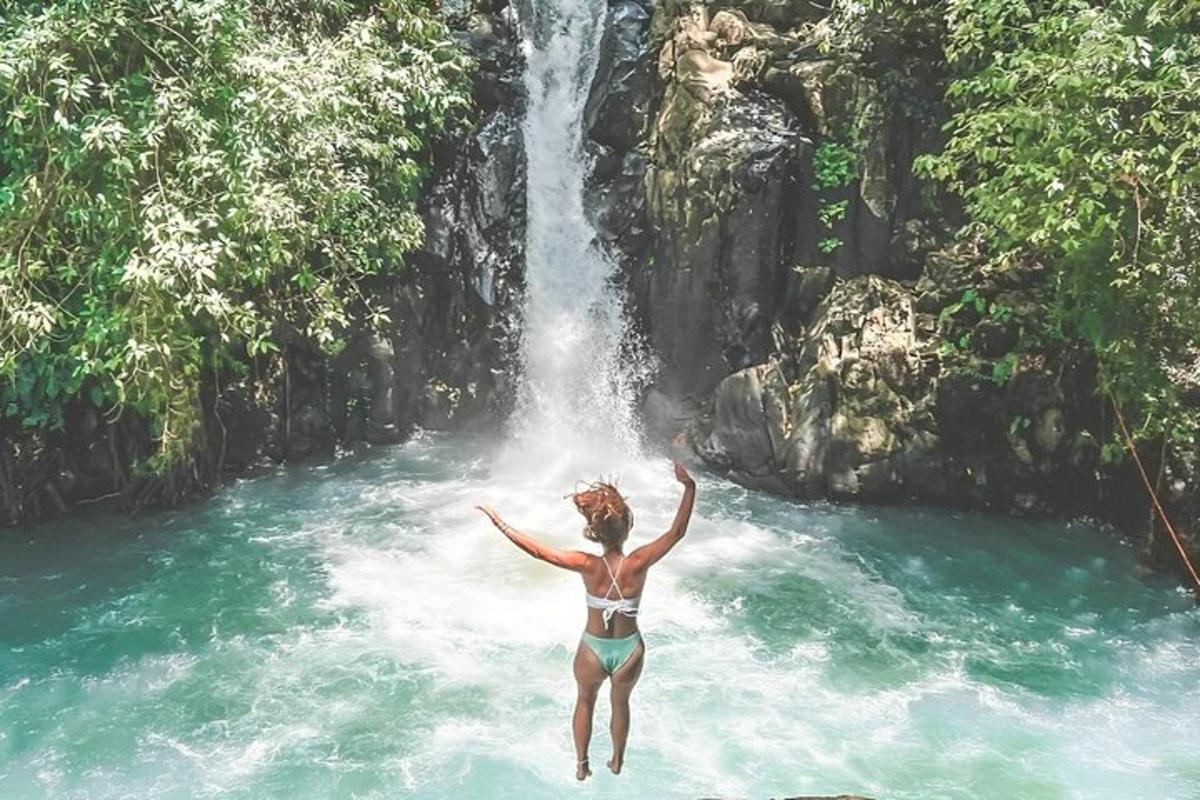 een vrouw in bikini die in een waterval springt
