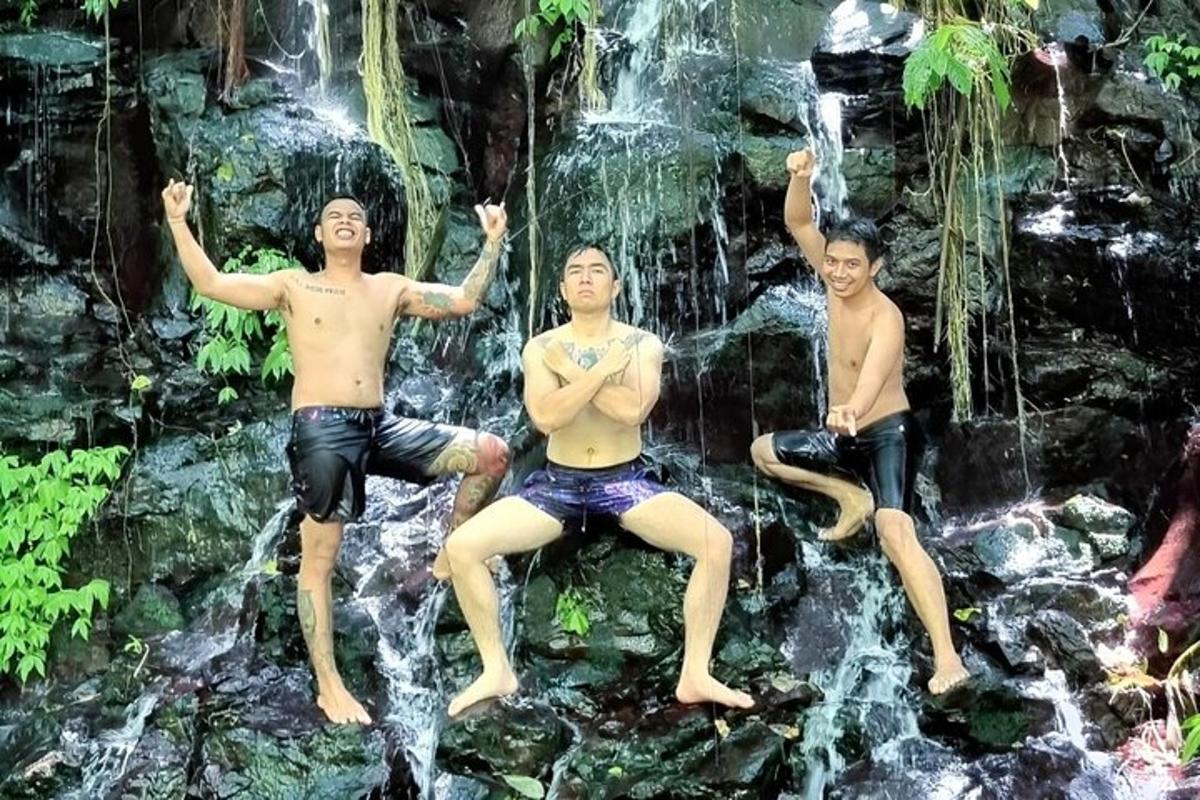三个男人坐在瀑布前的岩石上