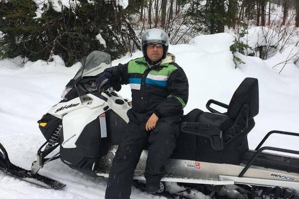 moški sedi na motornih saneh v snegu