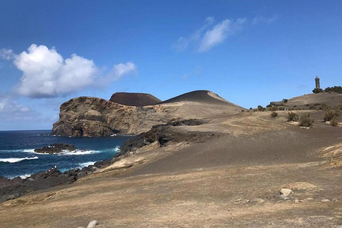a rocky hill with a lighthouse on it next to the ocean