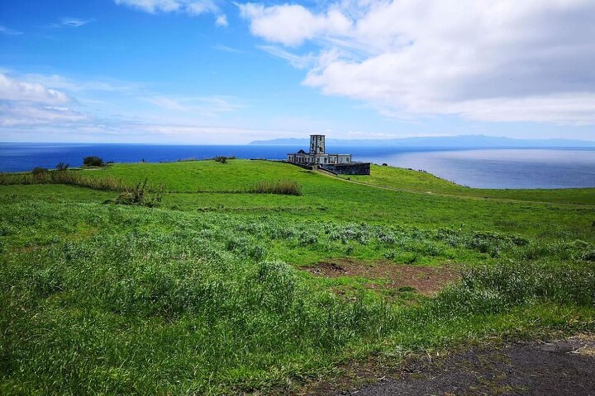 a house on top of a green hill with the ocean
