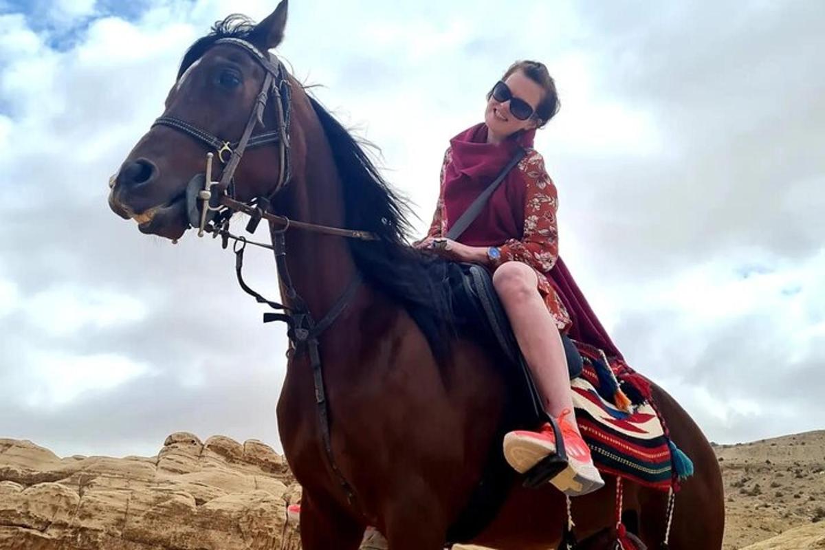 a woman sitting on a horse in the desert