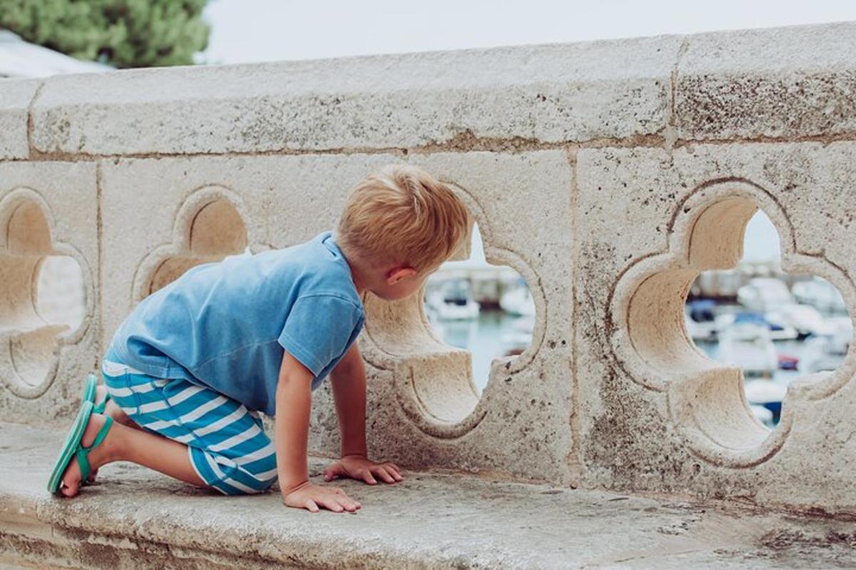 a young boy is sitting on a wall