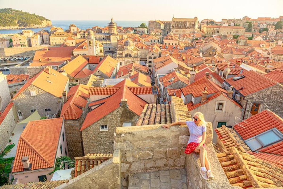 a woman sitting on top of a wall overlooking a city