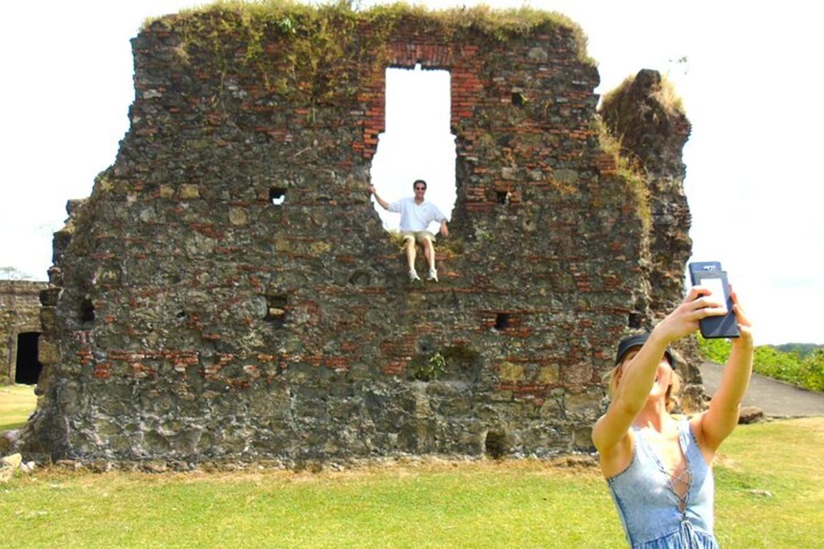a woman taking a picture of a man sitting on top of a building