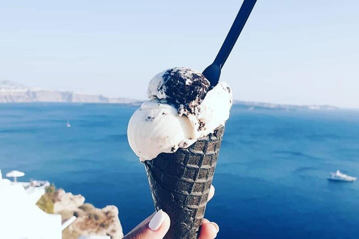 una persona che tiene in mano un cono gelato con l'oceano sullo sfondo