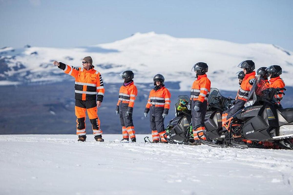 egy csoport ember áll a hóban egy motoros szánnal