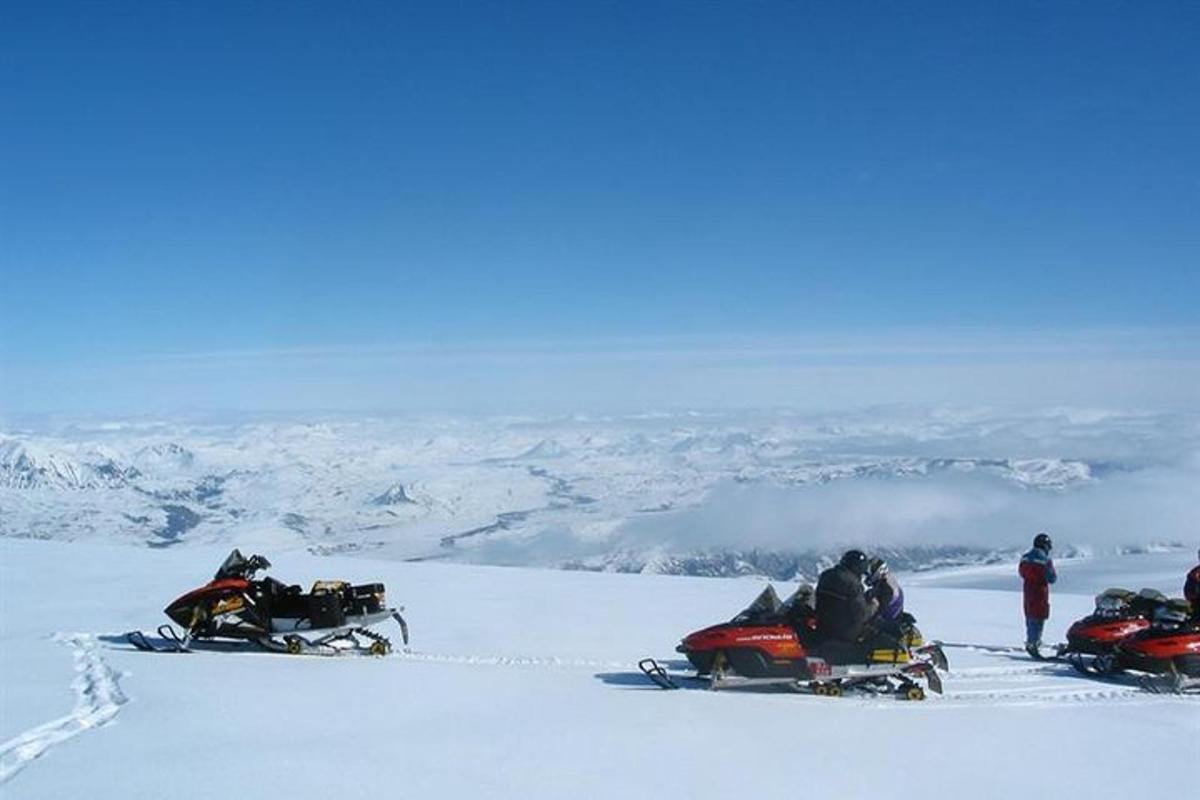 en gruppe mennesker på snøscootere på toppen av et fjell