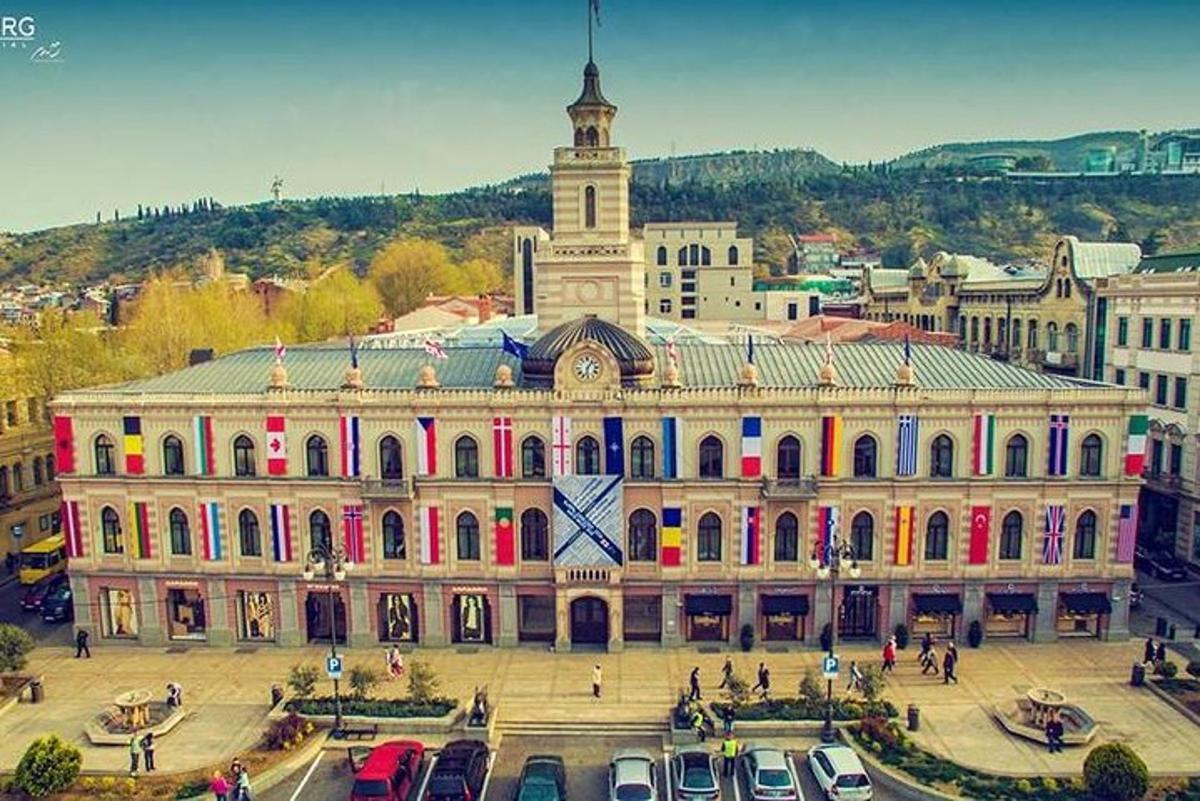 Un gran edificio con coches aparcados delante.