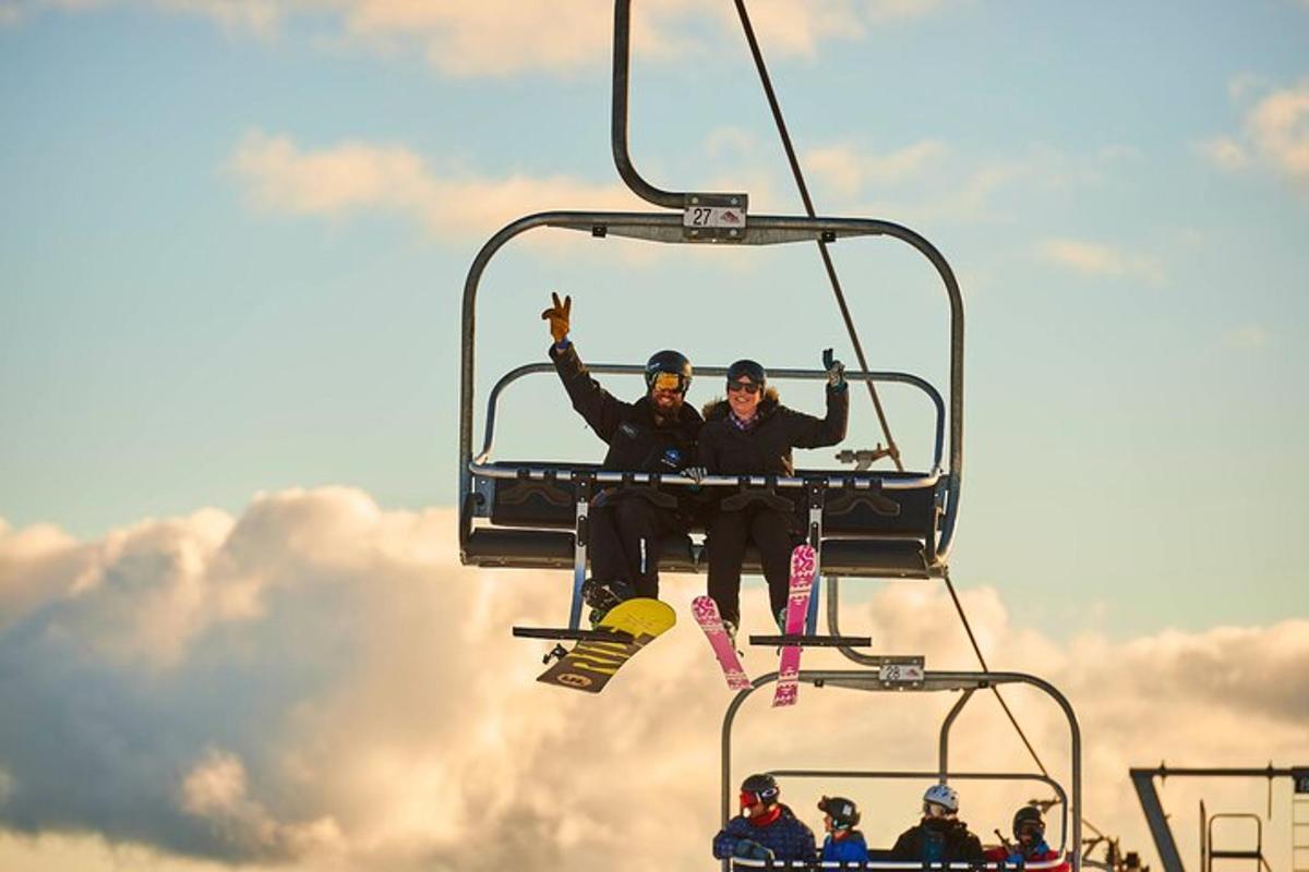 dalawang taong nakasakay sa ski lift gamit ang kanilang mga ski