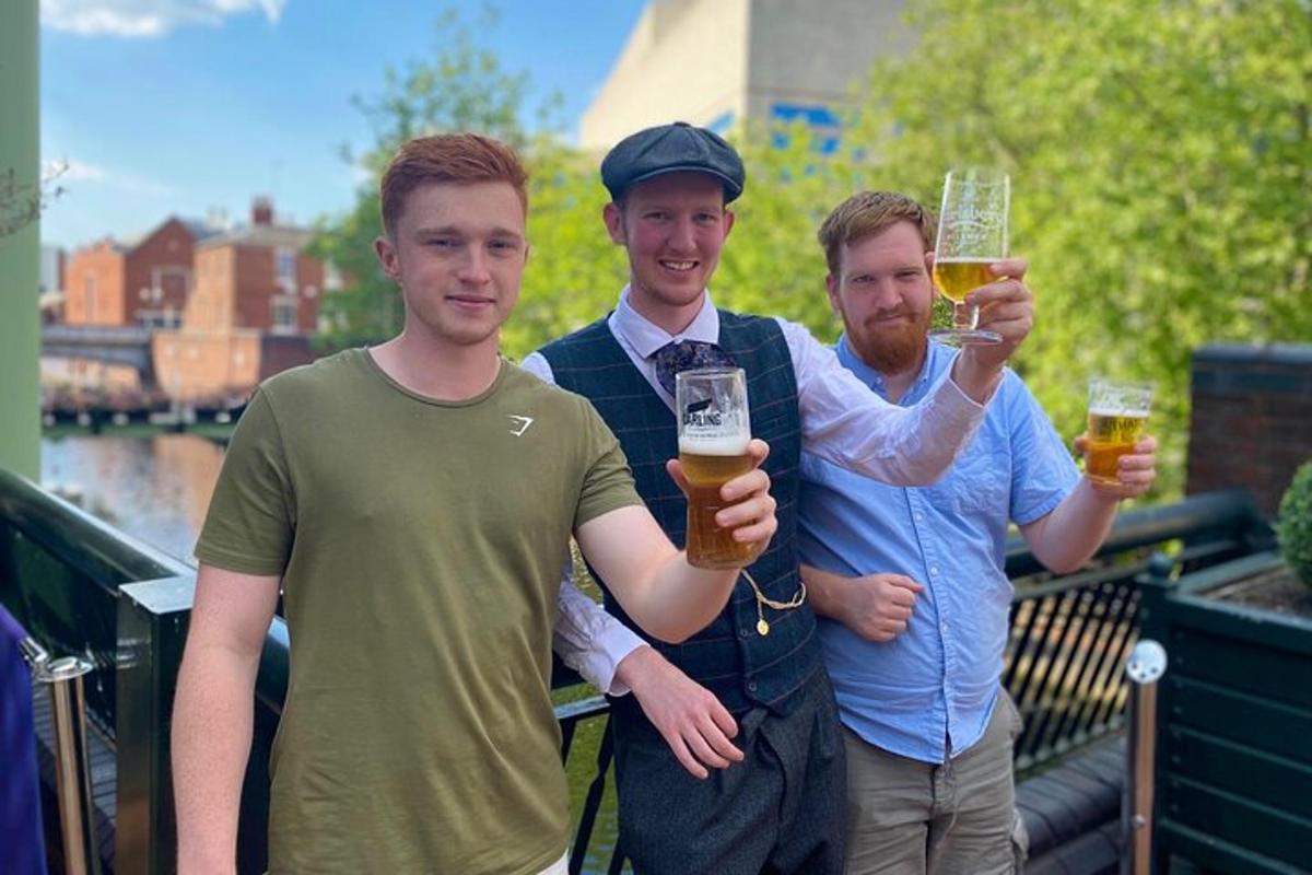 tre uomini che tengono bicchieri di birra su un balcone