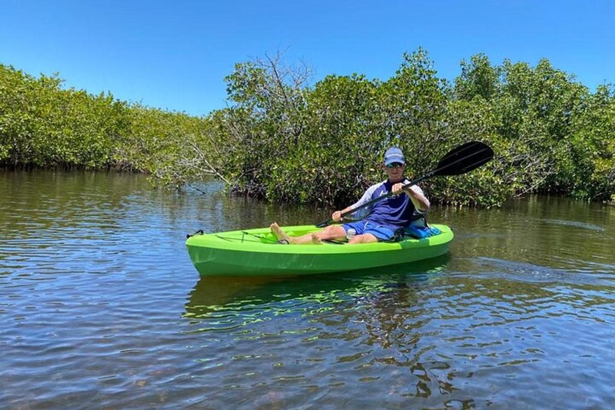 a man is sitting in a green kayak on the water