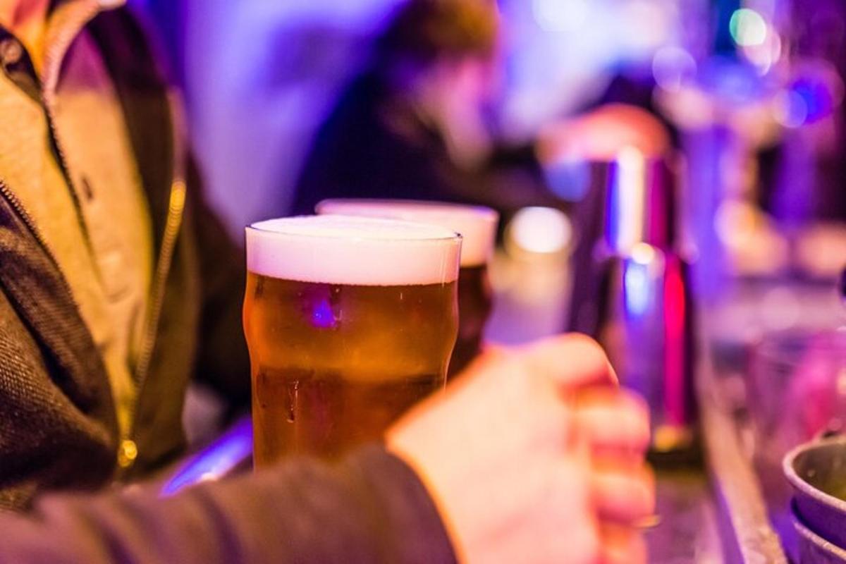 een persoon die een glas bier vasthoudt op een bar