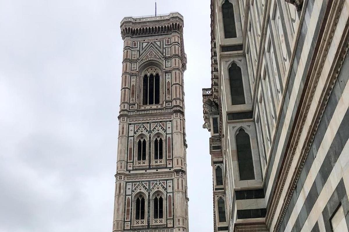 Un edificio alto con una torre de reloj al lado de dos edificios.
