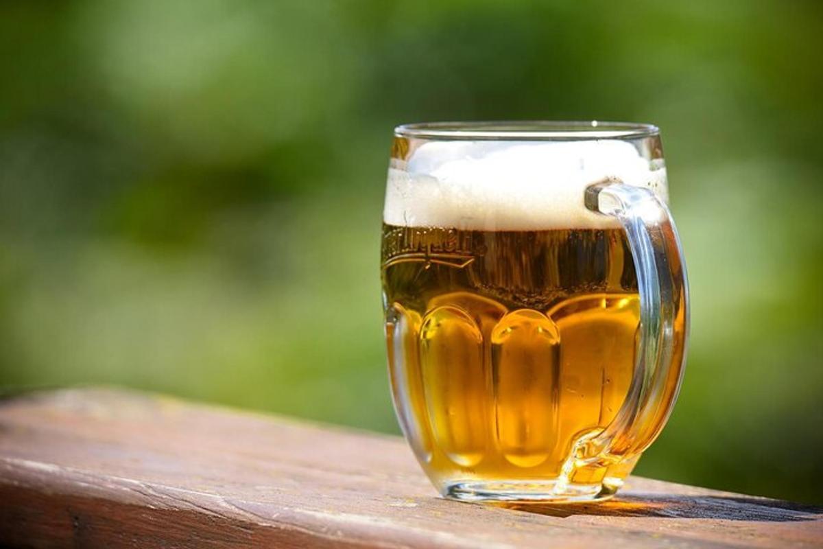 sklenice piva stojící na dřevěném zábradlí