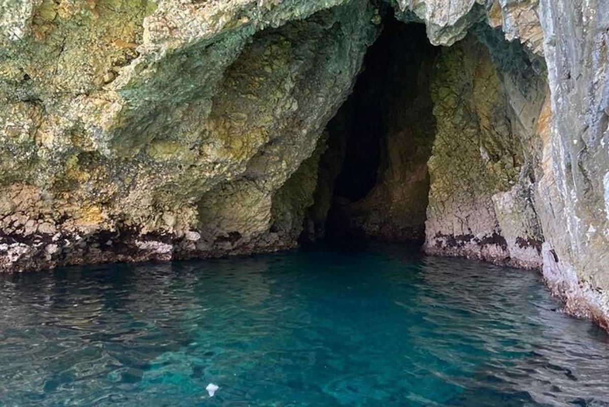 a cave with blue water in front of a cliff