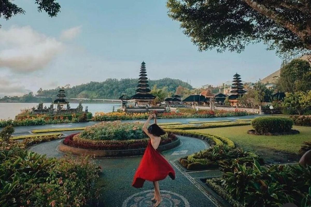 seorang wanita bergaun merah berdiri di air mancur