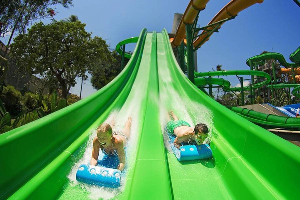 two children sliding down a slide at a water park