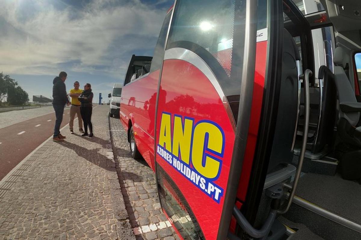 un grup de persones dempeus al costat d'un autobús vermell