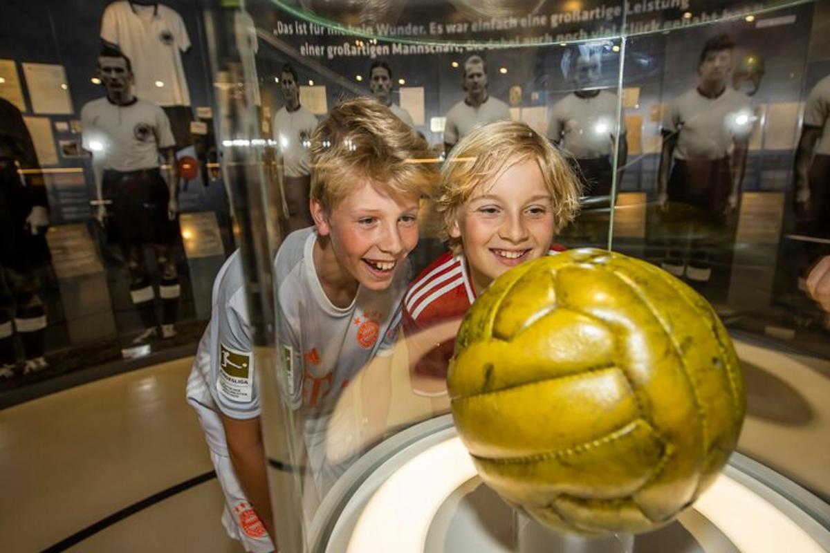 two girls are looking at a soccer ball in a display case