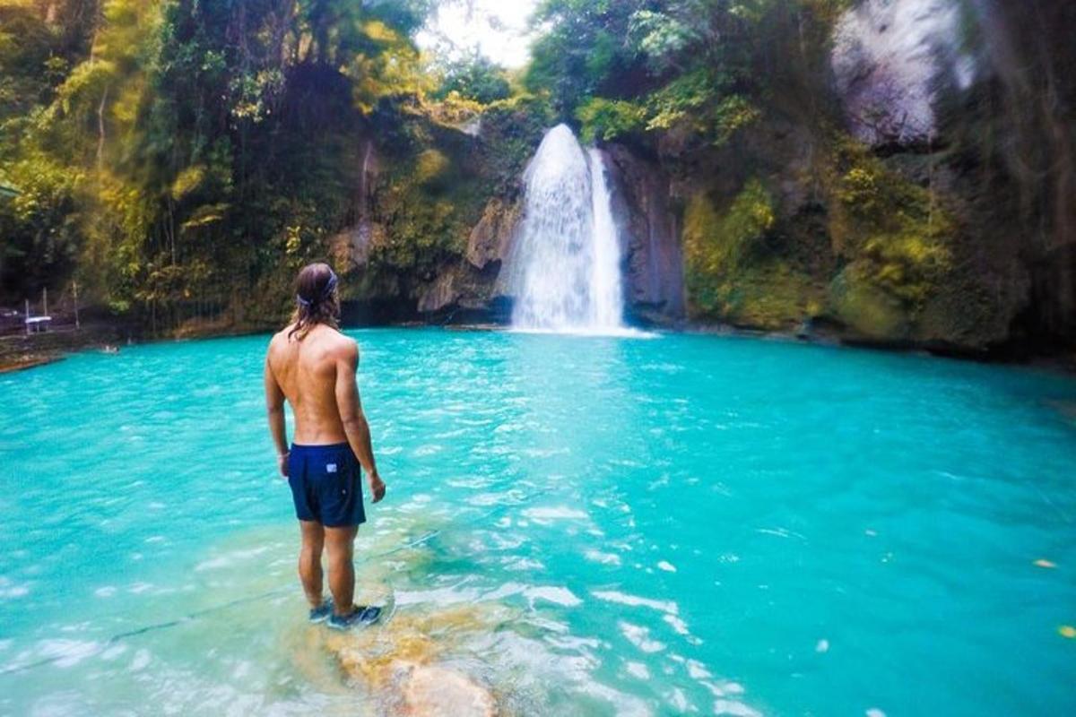 Un hombre parado en el agua frente a una cascada.