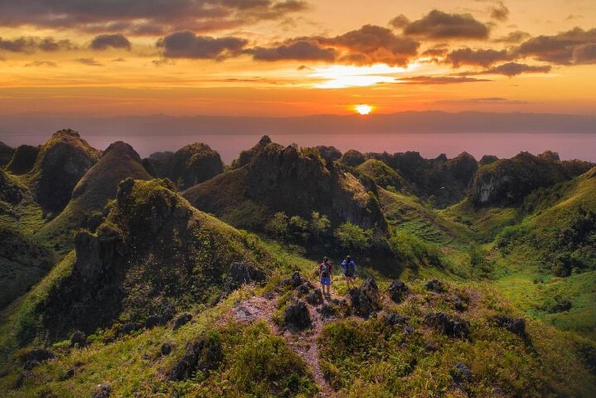 um grupo de pessoas caminhando em uma montanha ao pôr do sol