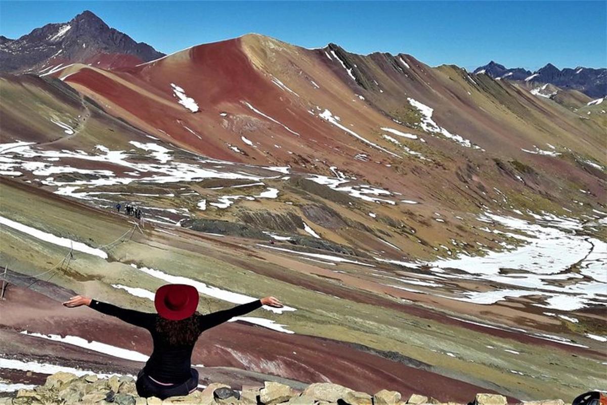 eine Person, die auf einem Felsen sitzt und auf einen Berg blickt