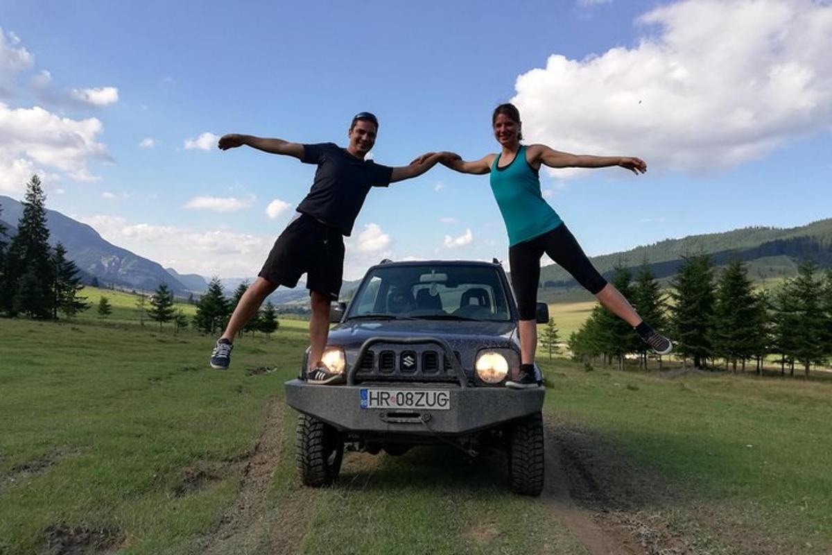 a man and a woman jumping in front of a jeep