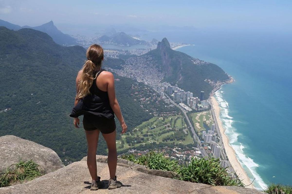 uma mulher em pé no topo de uma montanha com vista para o oceano