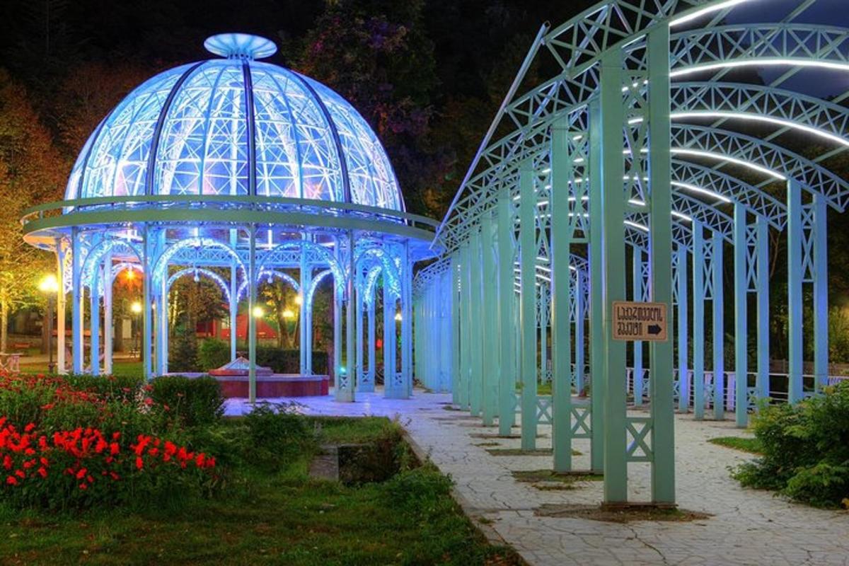 Un edificio azul con un mirador en un jardín por la noche.