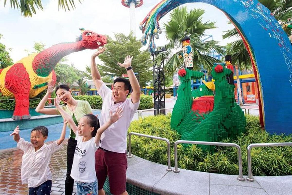 a woman and two children standing in front of a dinosaur park