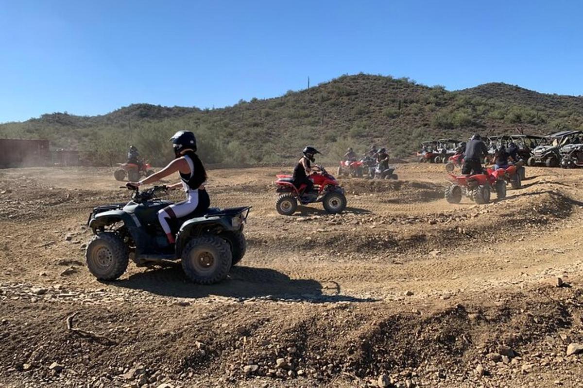 un grup de persones que van en quads en un camp de terra