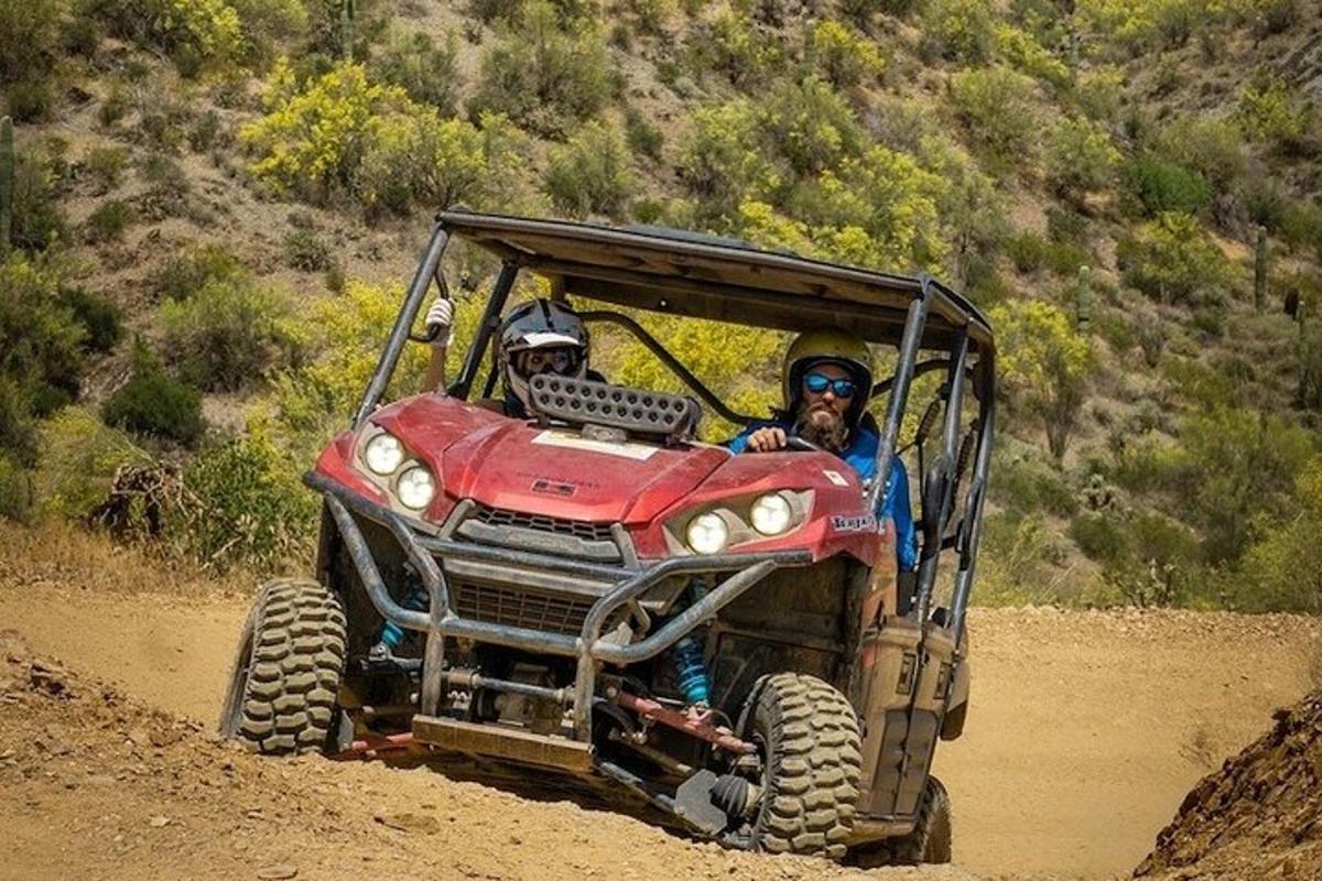duas pessoas andando em um quadriciclo vermelho em uma estrada de terra