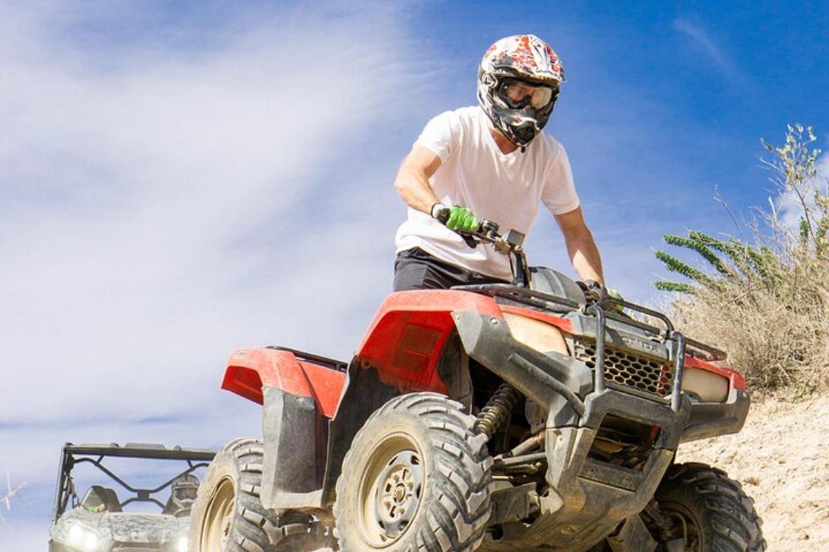 un home muntant un quad a la platja