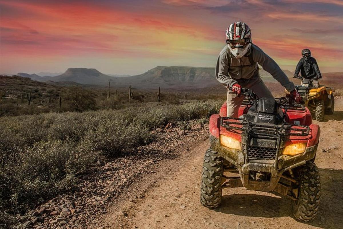 two people riding on a four wheeler on a dirt road