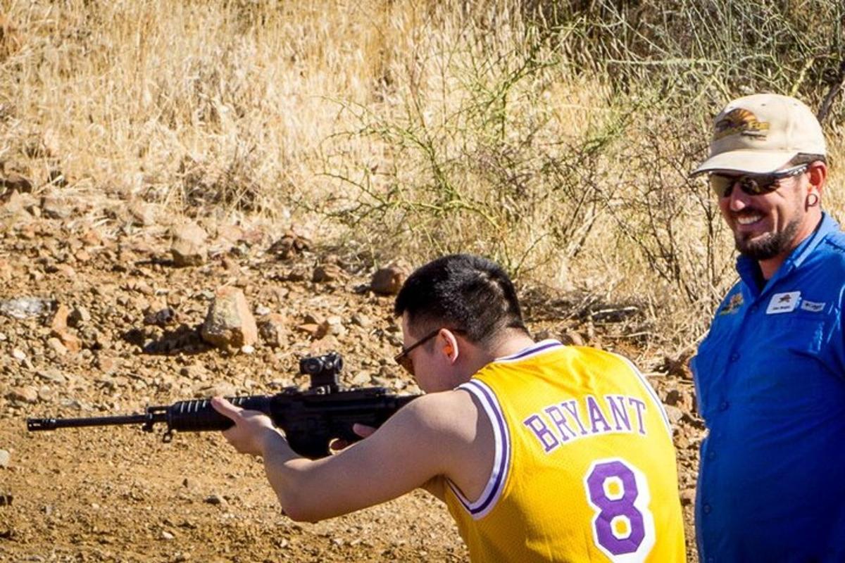 seorang lelaki memegang pistol di sebelah seorang lelaki