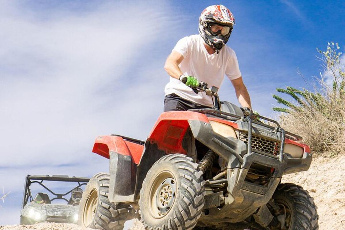 Un hombre conduciendo un quad en la arena