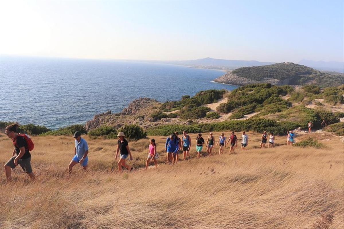 um grupo de pessoas caminhando em uma colina perto do oceano