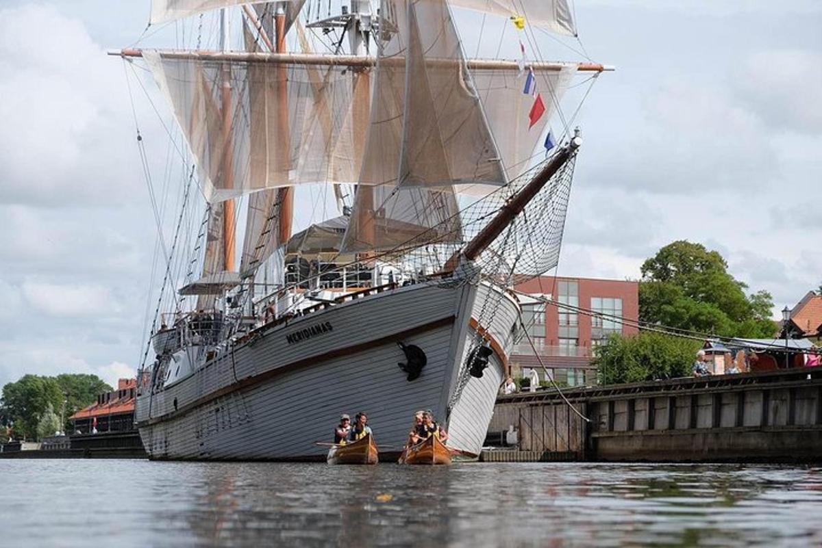un gruppo di persone in kayak di fronte a una nave alta